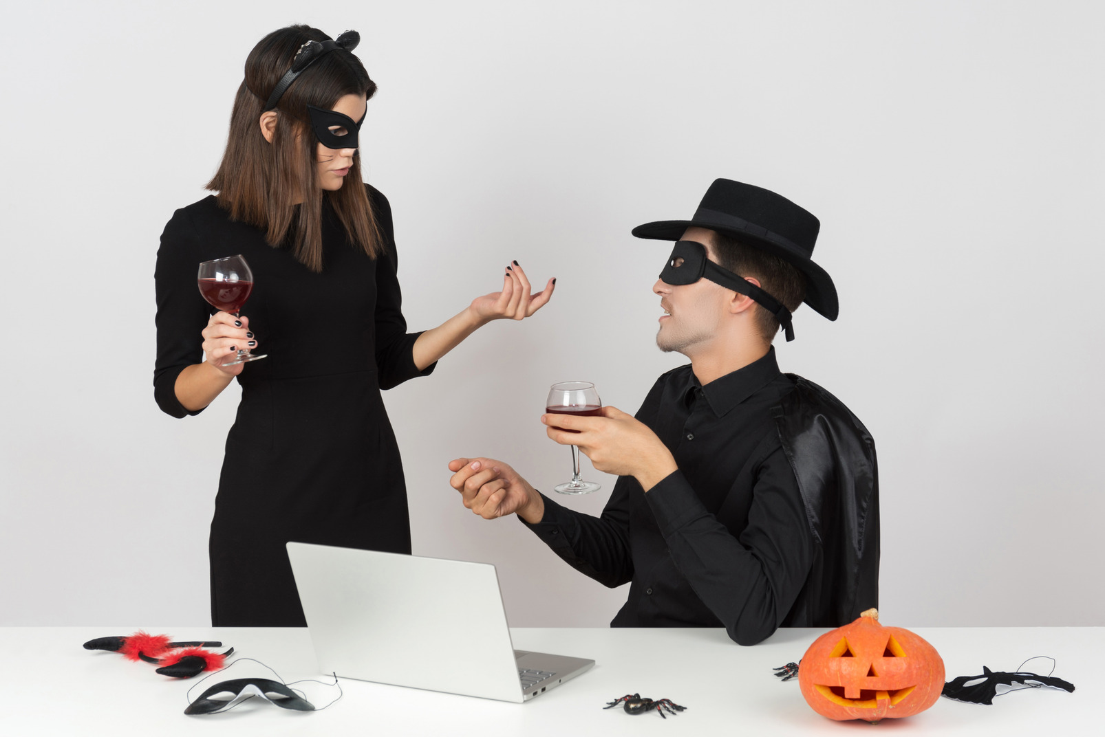 Woman in cat costume and her coworker in zorro costume looking at something at notebook