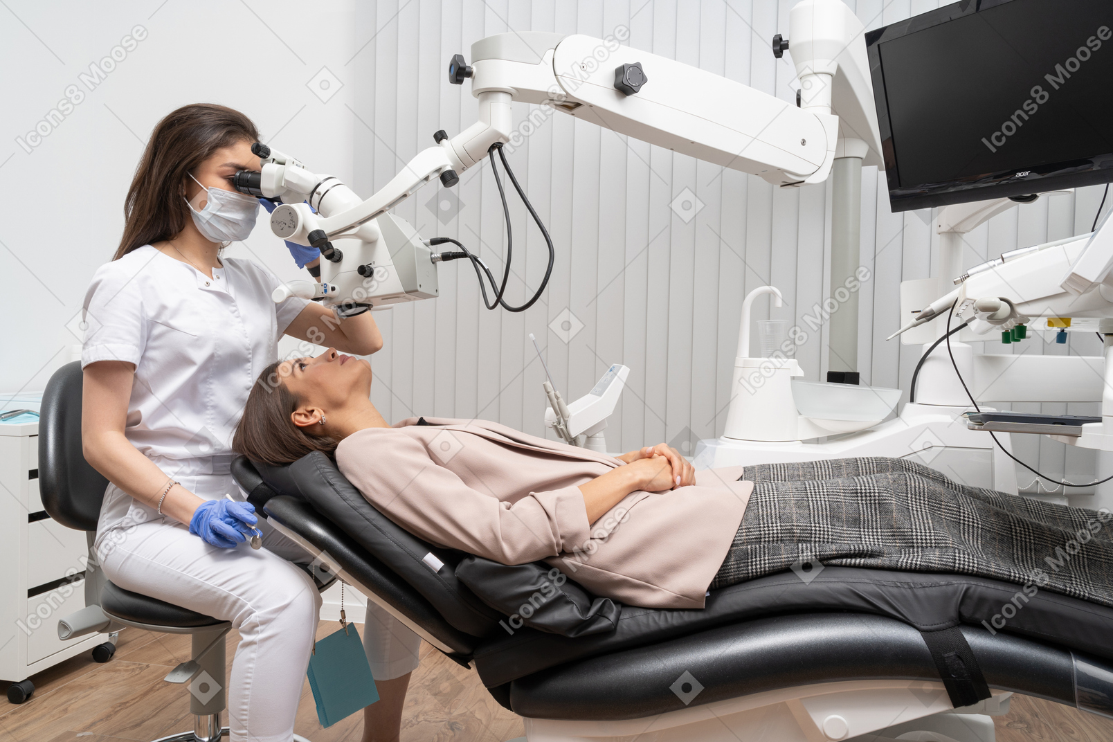 Женщина-стоматолог в полный рост осматривает свою пациентку и смотрит в микроскоп