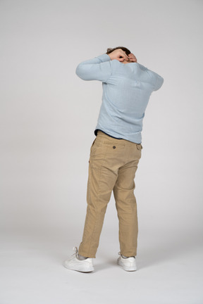 Rear view of a boy standing with hands behind head