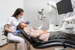 Full-length of a female dentist examining her patient with a mirror