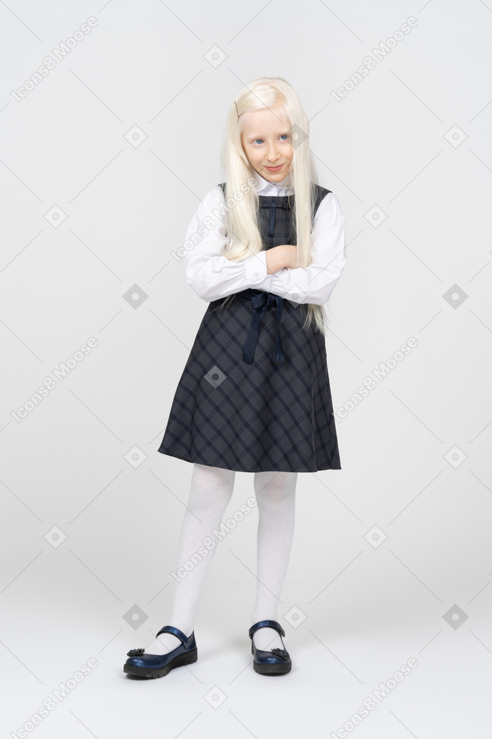 Schoolgirl smiling while standing with arms crossed