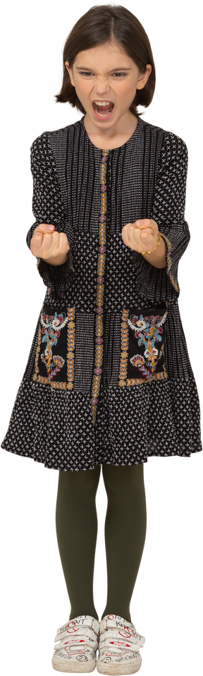 Вид спереди разъяренной маленькой девочки в платье сжимая кулаки
