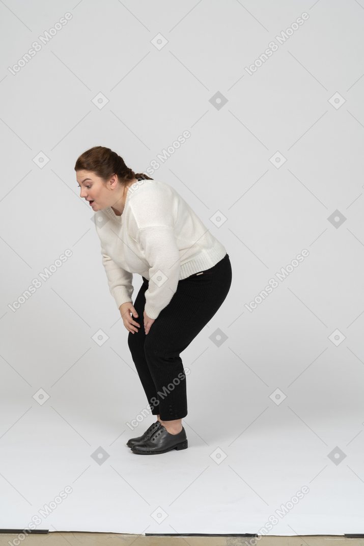 Vista laterale di una donna grassoccia in abiti casual che tocca le ginocchia