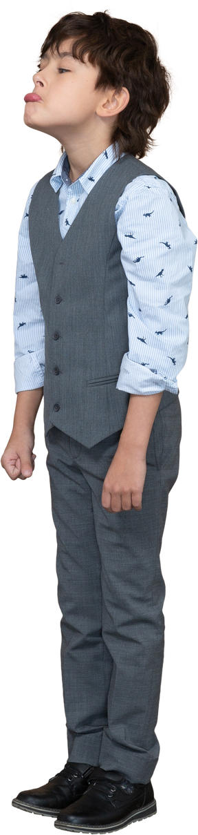 Vista lateral de un chico lindo en traje gris haciendo muecas