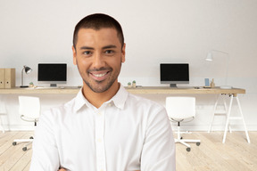 A man standing in an office with his arms crossed