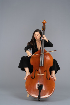 Front view of a young lady sitting on a chair while putting legs on double-bass