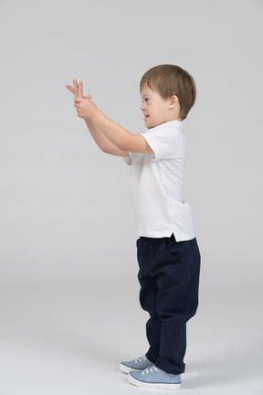 Side view of little boy holding his hand up