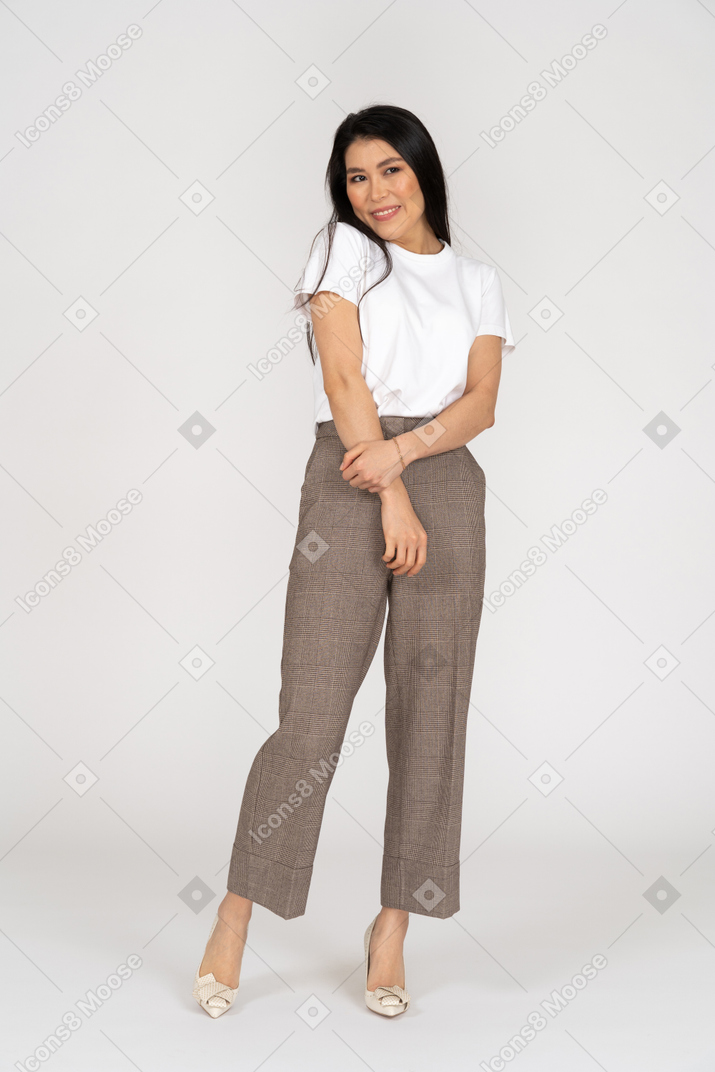 Vista frontal de una tímida señorita sonriente en calzones y camiseta tomados de la mano juntos