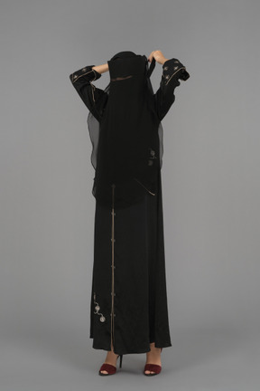 A muslim woman putting on a niqab