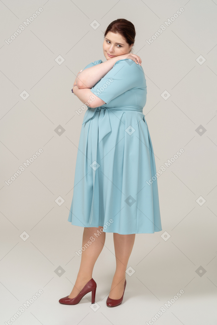 Front view of a woman in blue dress hugging herself