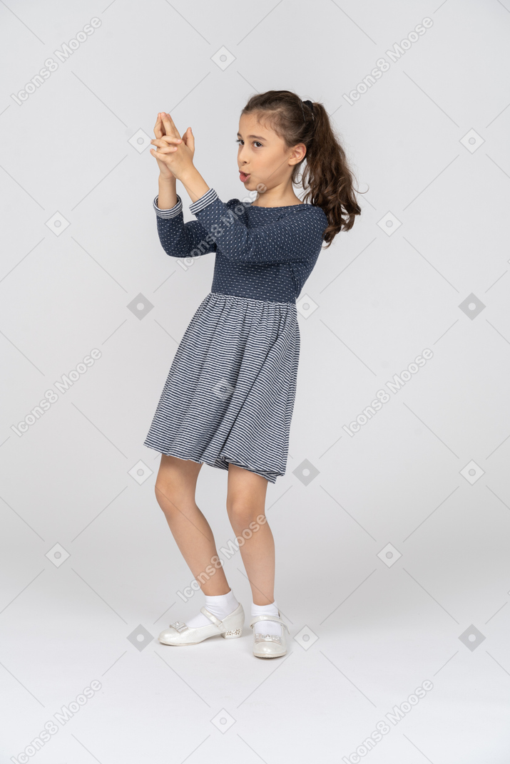 Three-quarter view of a girl making a finger gun with her hands