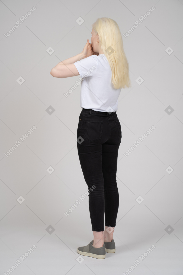 Vista posteriore di una donna dai capelli lunghi che si copre la bocca