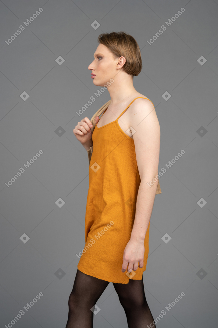 Vista laterale di una giovane persona queer che cammina con la borsa sulla spalla