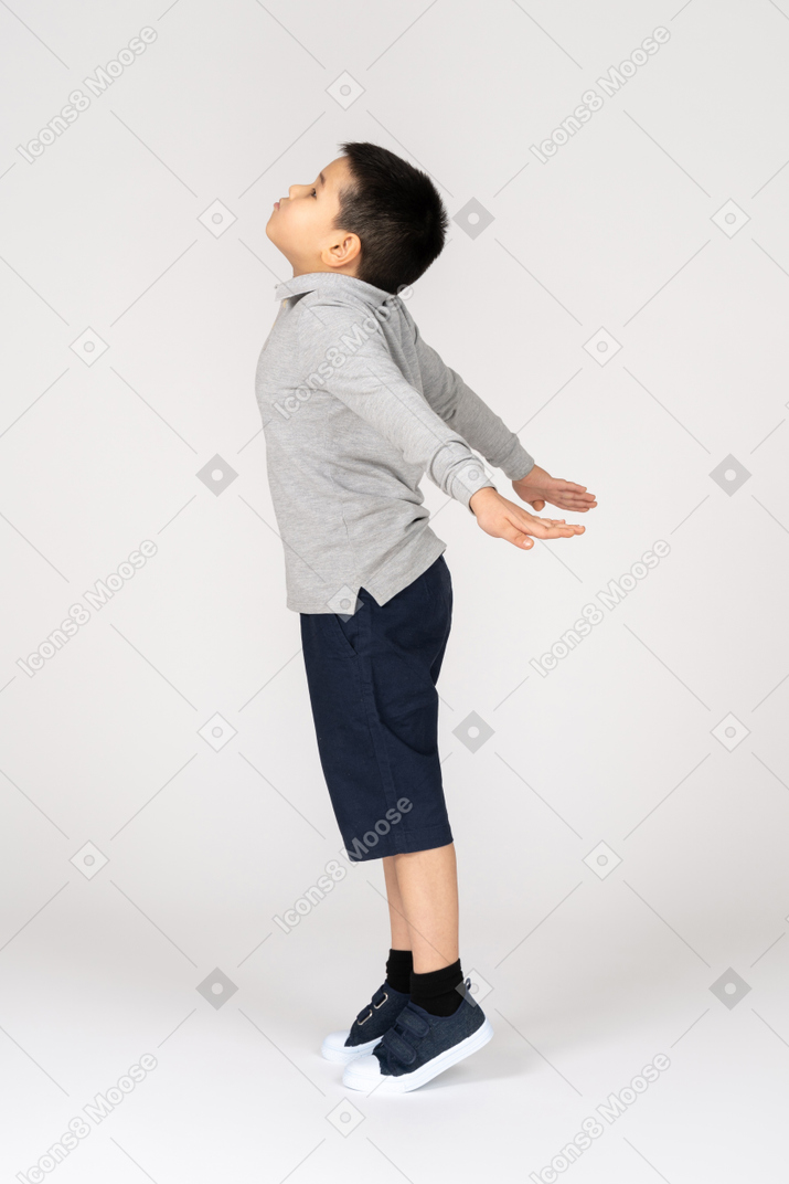 Niño mirando hacia arriba con los brazos abiertos