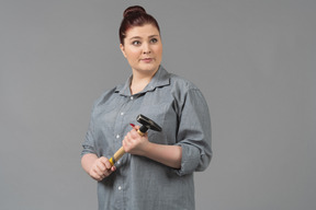 Young woman looking sideways with hammer in hands