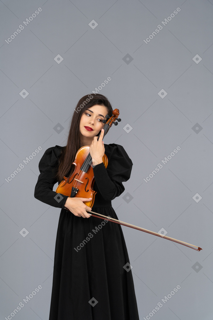 Primo piano di una giovane donna in abito nero che abbraccia il suo violino