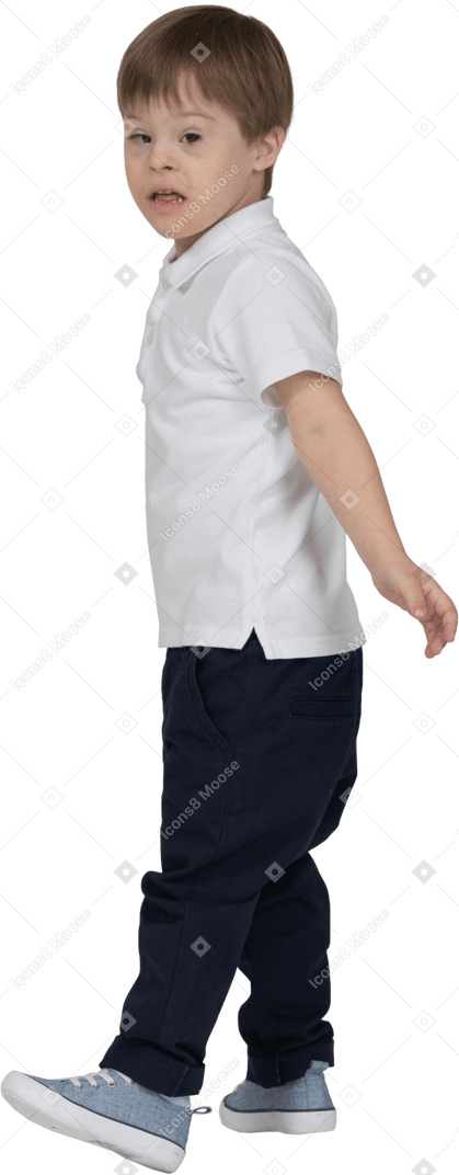 Vue latérale d'un garçon marchant avec les bras sur les côtés