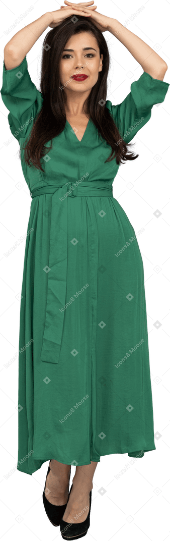 頭に手を置いて緑のドレスを着た若い女性の正面図