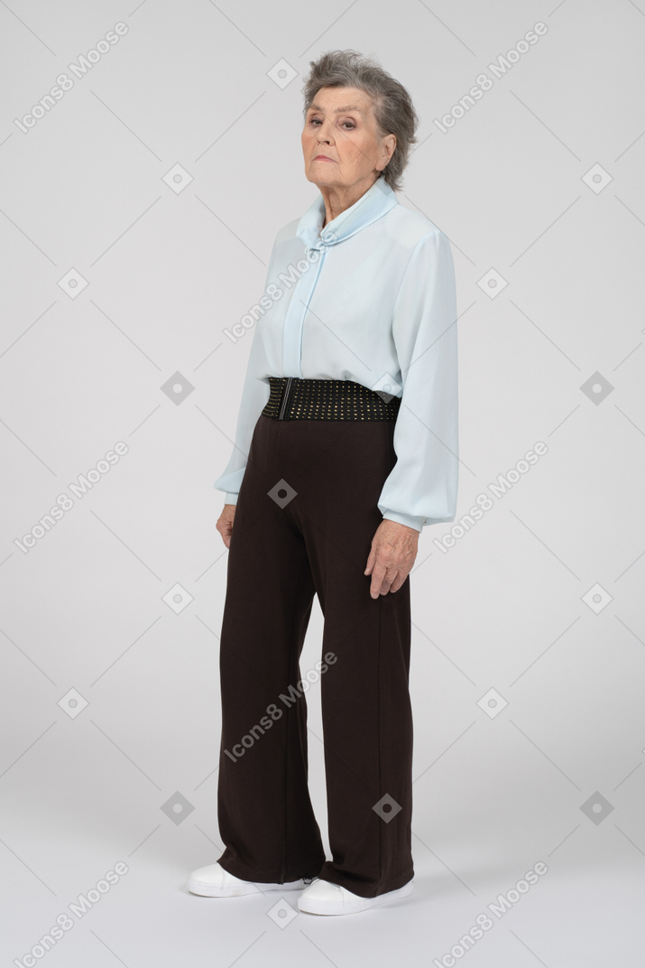 Вид в три четверти на пожилую женщину, стоящую и смотрящую вниз