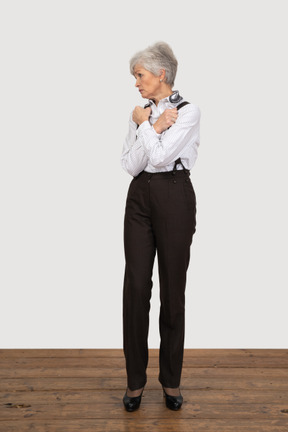 Vista frontal de una anciana en ropa de oficina cruzando las manos y apretando los puños