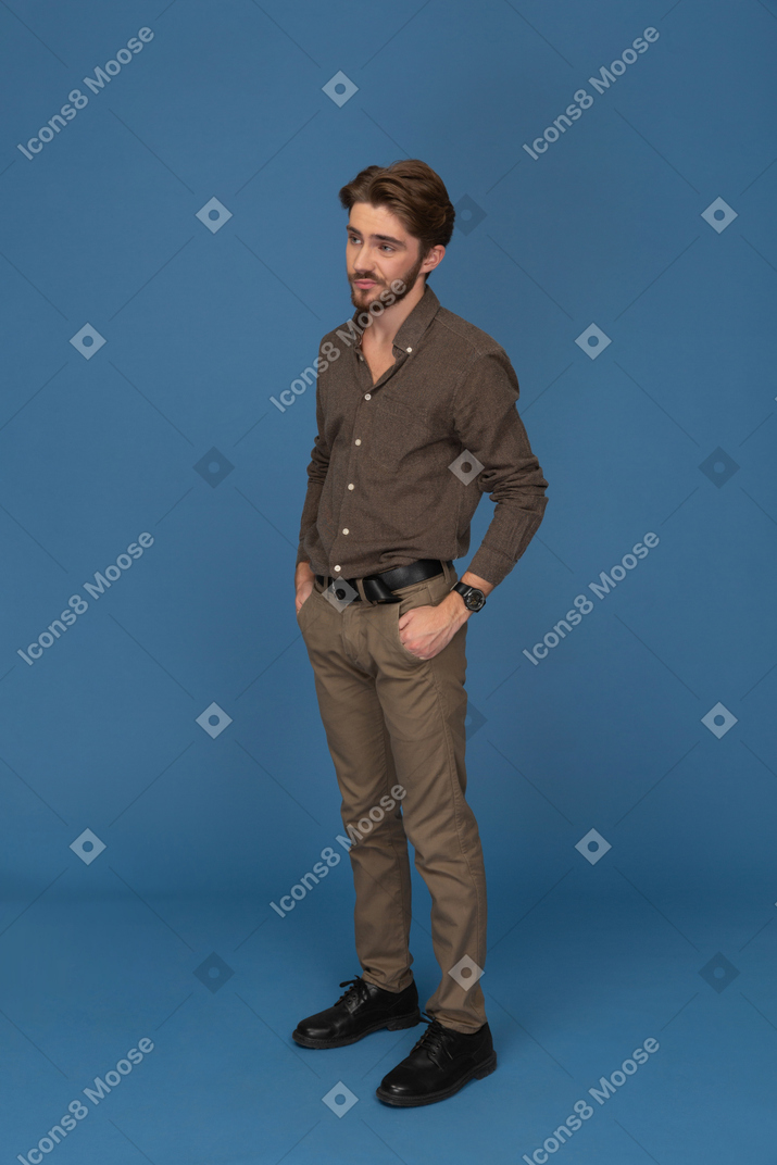 Sceptical young man standing with hands in pockets