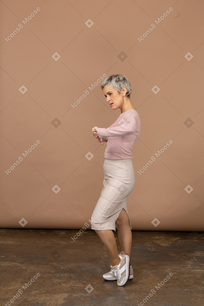 Vista lateral de una mujer en ropa casual mostrando los pulgares hacia abajo