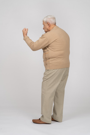 Side view of an old man in casual clothes showing fist