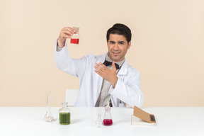 Worried male scientist sitting at the table and looking at bulb
