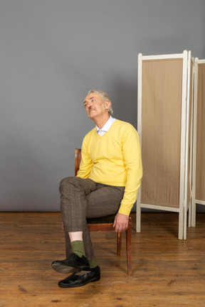 Hombre sentado en una silla y mirando a otro lado