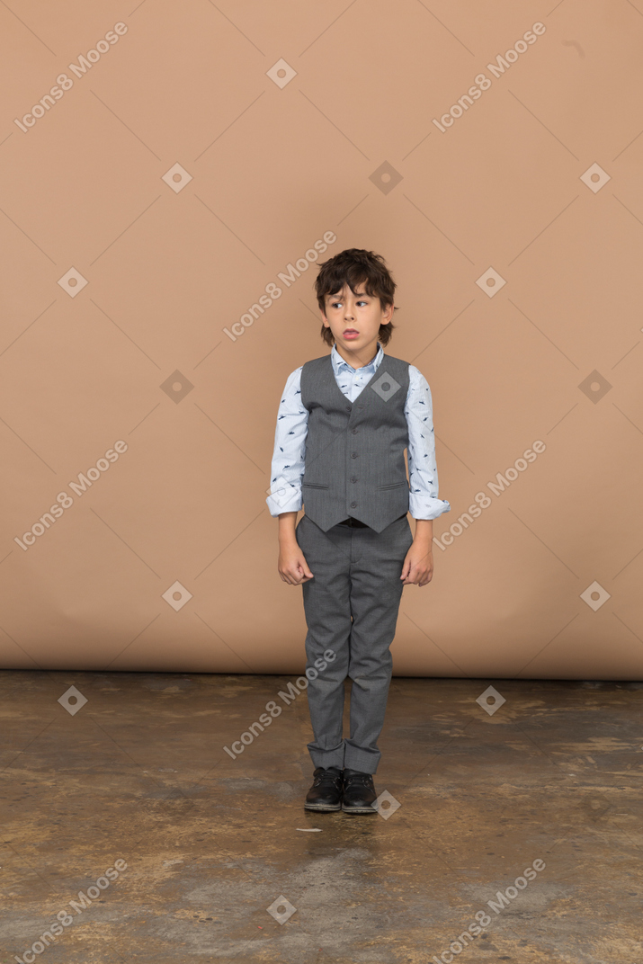 一个穿着西装的男孩站着不动的前视图