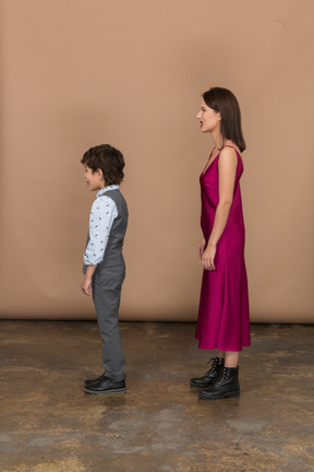 Disgusted woman in red dress and boy standing in profile