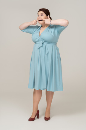 Front view of a woman in blue dress touching her mouth
