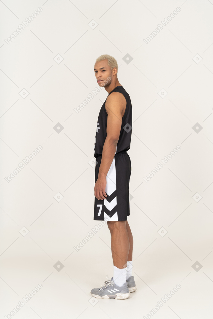 Vista posteriore di tre quarti di un seducente giovane giocatore di basket che si morde le labbra