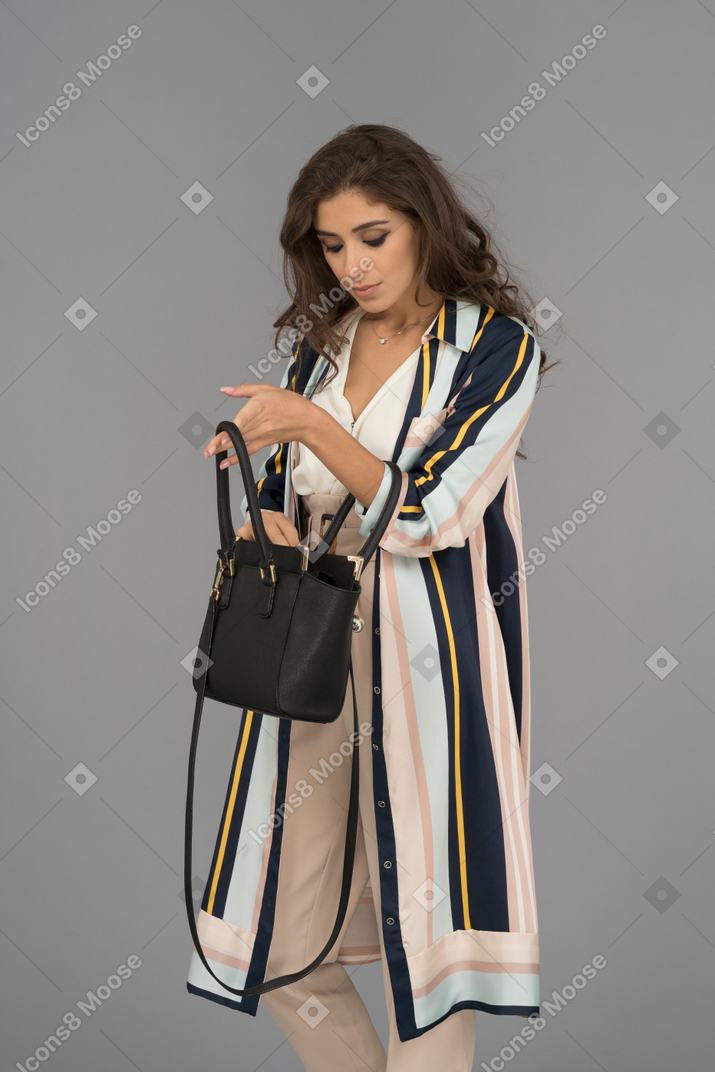 Attractive young woman looking for keys in her handbag