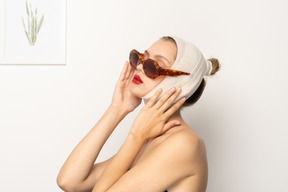 Woman with bandaged head and sunglasses touching her face