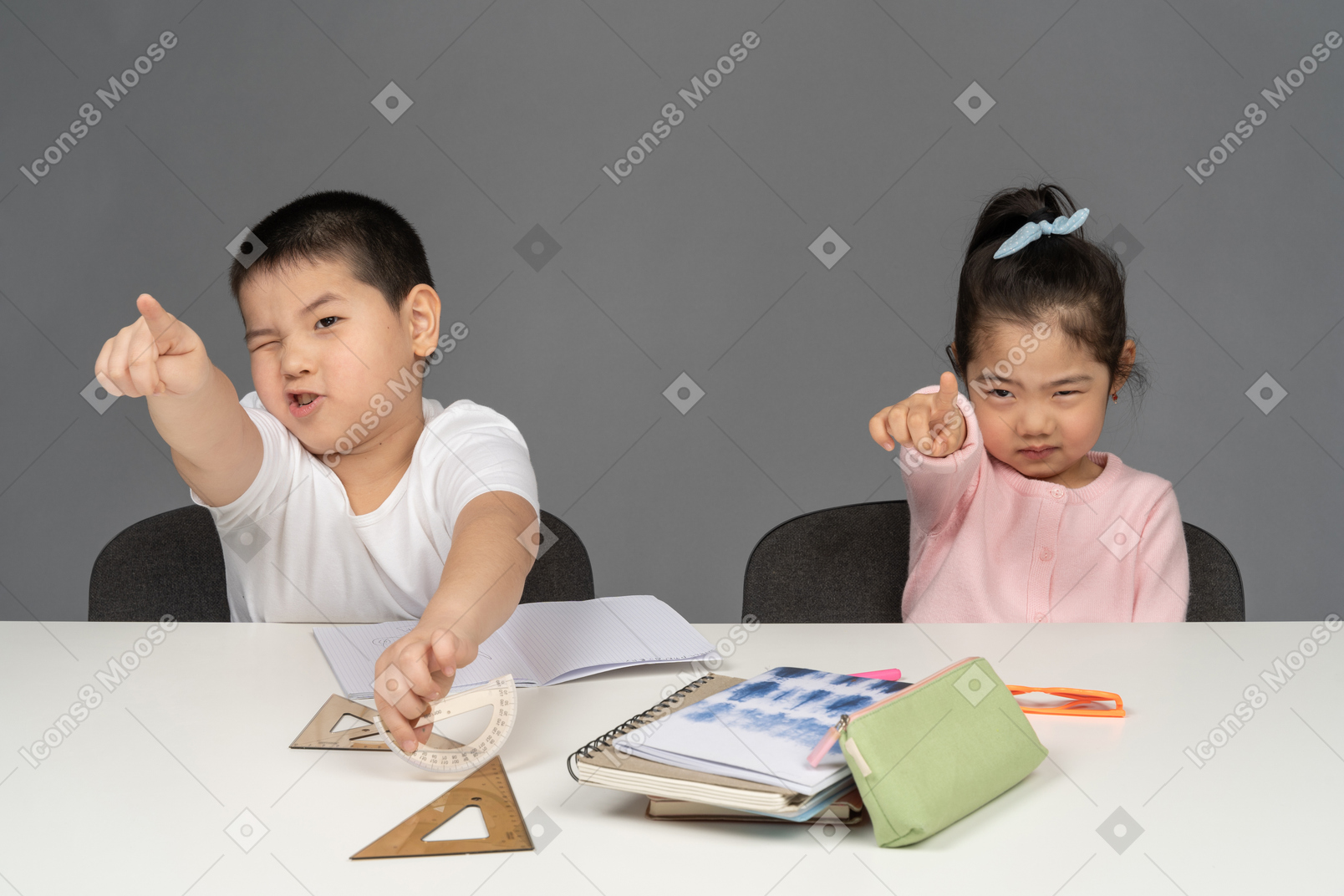 机に座って前を指している男の子と女の子