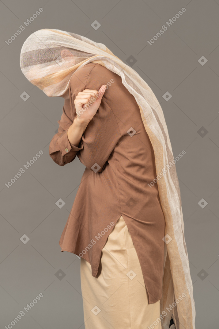Scared woman with scarf on her head holding hands crossed