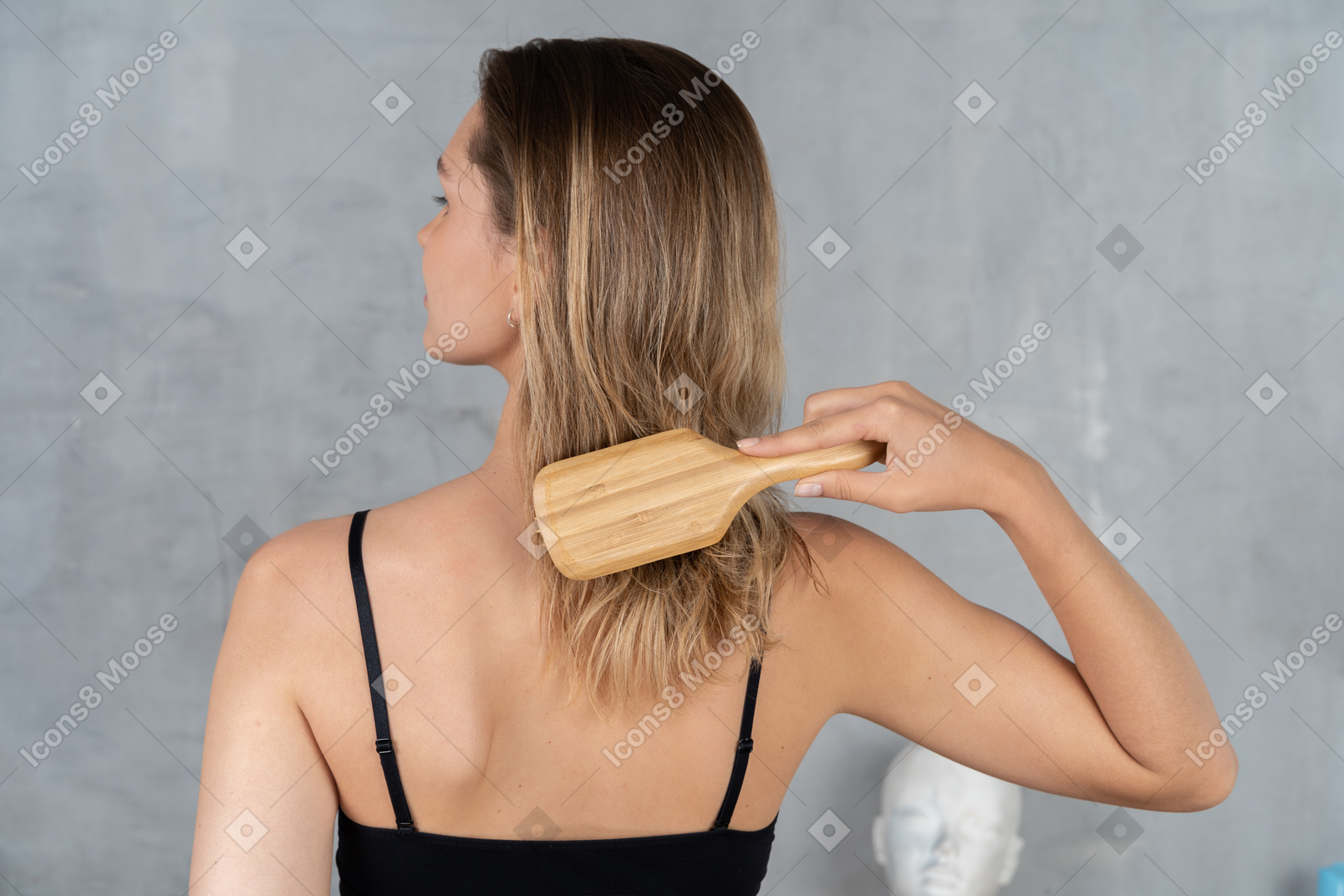 Vista posteriore di una giovane donna che si spazzola i capelli