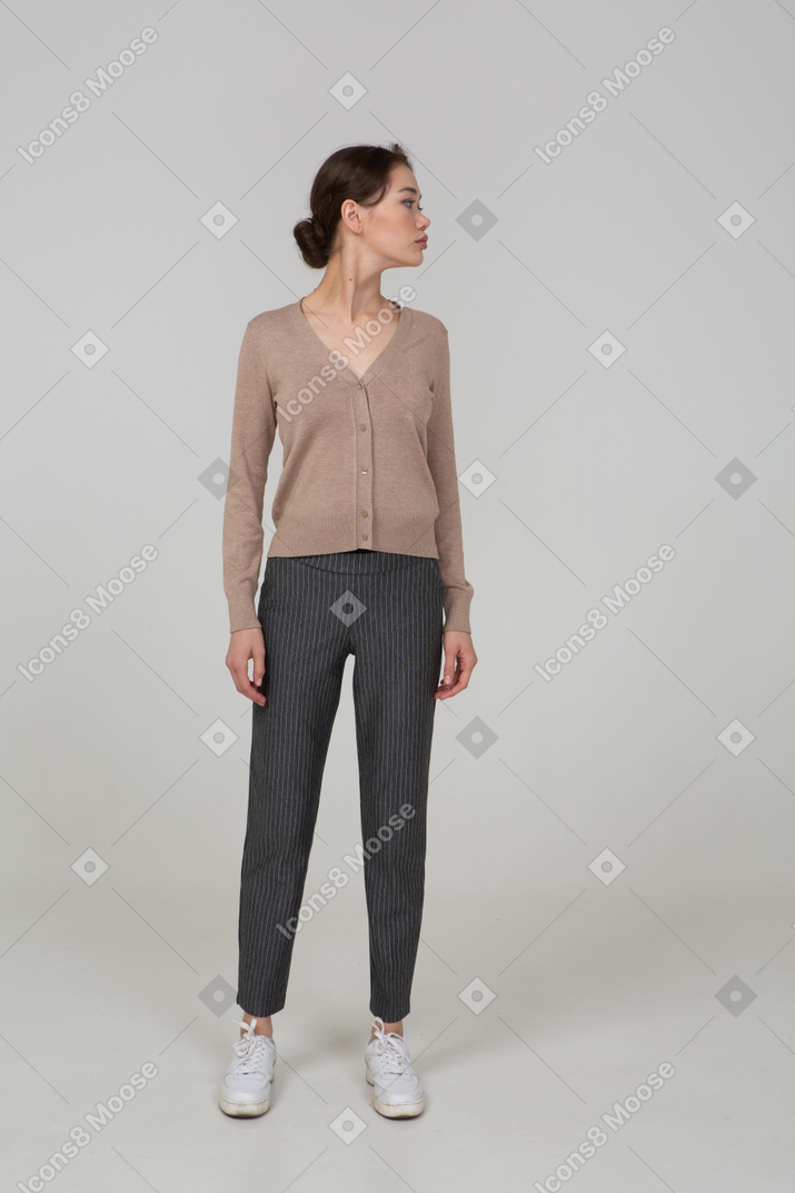 Vista frontal de una joven en suéter y pantalones girando la cabeza hacia la derecha