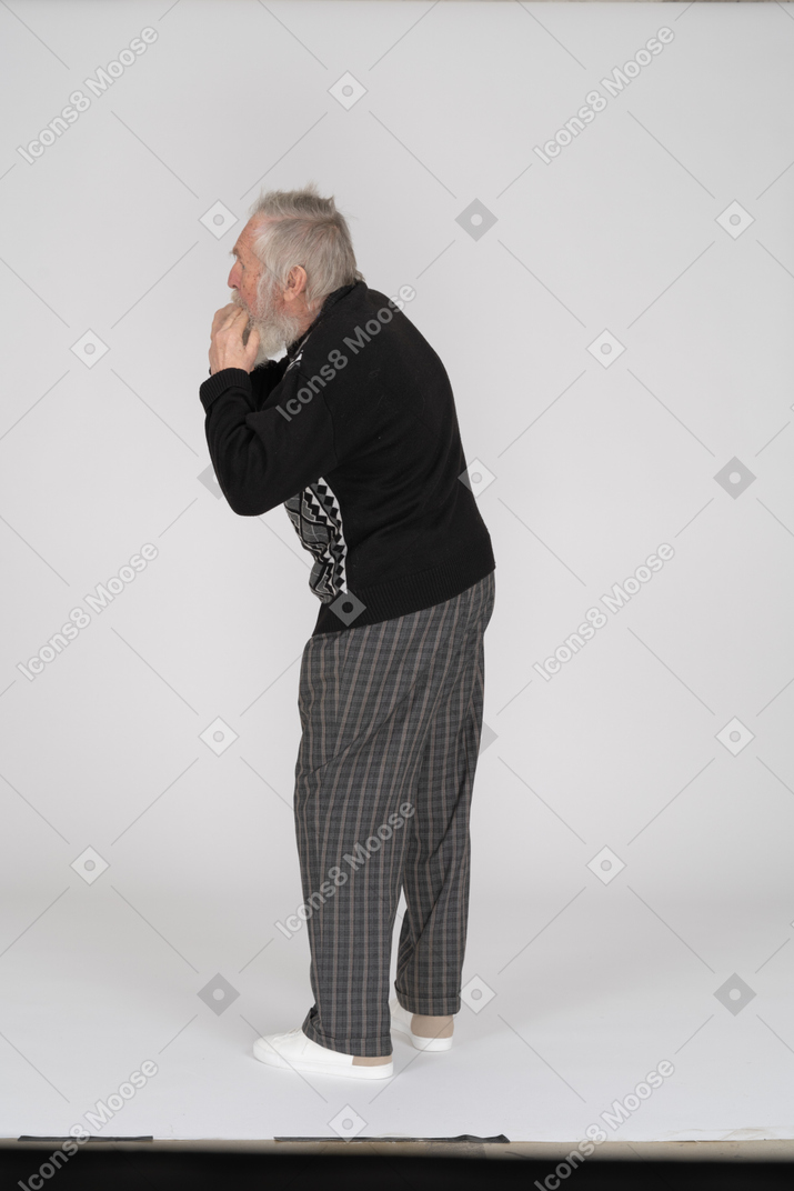Rear view of old man with hands in mouth