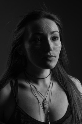 Head to shoulder noir portrait of a hopeful young female with face art looking aside