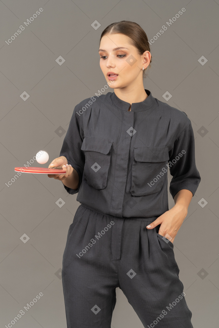 Vista di tre quarti di una giovane donna in tuta che gioca a ping pong