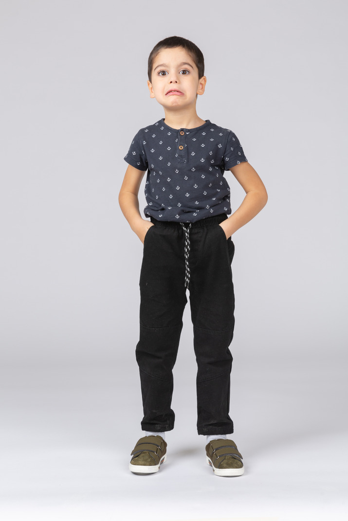 Front view of a boy posing with hands in pockets and making faces