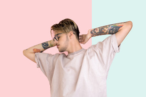 Young man with tattoos standing with his hand on his nape