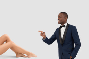 A man in a tuxedo pointing at a woman's legs