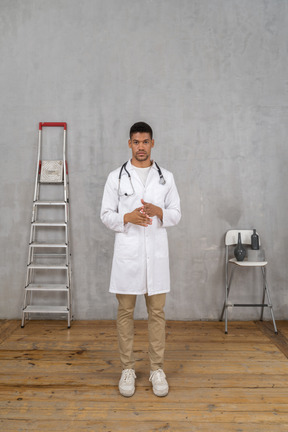 Front view of a young doctor standing in a room with ladder and chair