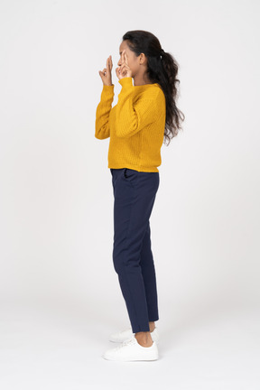 Vista lateral de uma garota com roupas casuais apontando para cima com os dedos
