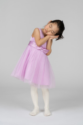 Сонная маленькая девочка в розовом платье стоит