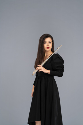 Three-quarter view of a serious young lady in black dress holding flute