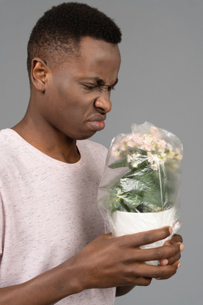 Jeune homme n'aime pas l'odeur de la fleur